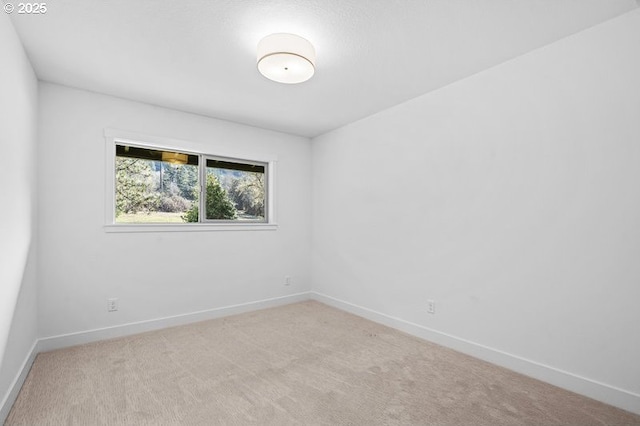 spare room with light carpet and baseboards