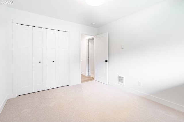 unfurnished bedroom with carpet floors, a closet, visible vents, and baseboards