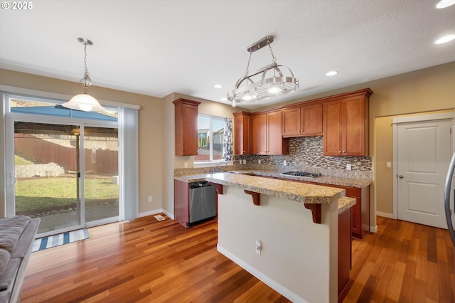 kitchen with tasteful backsplash, a kitchen breakfast bar, a kitchen island, pendant lighting, and stainless steel appliances