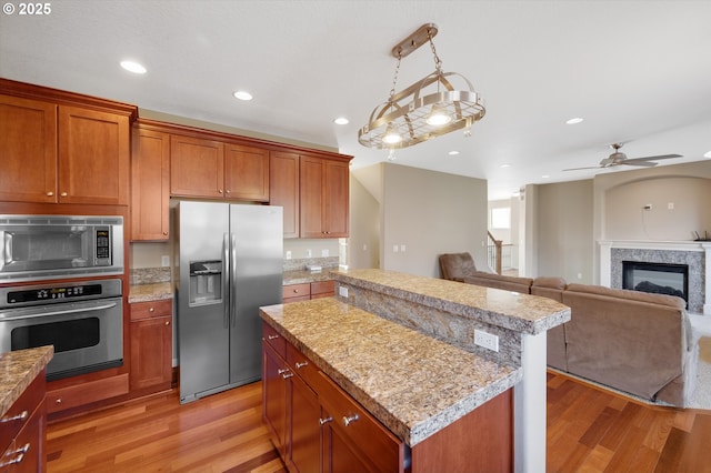 kitchen featuring decorative light fixtures, a kitchen island, light hardwood / wood-style floors, and appliances with stainless steel finishes