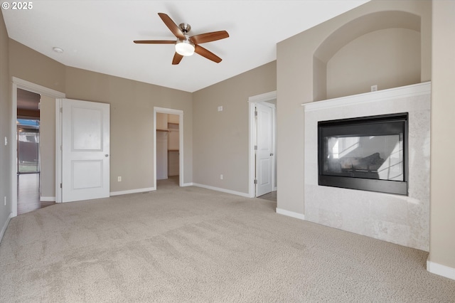 unfurnished living room featuring a multi sided fireplace, light colored carpet, and ceiling fan