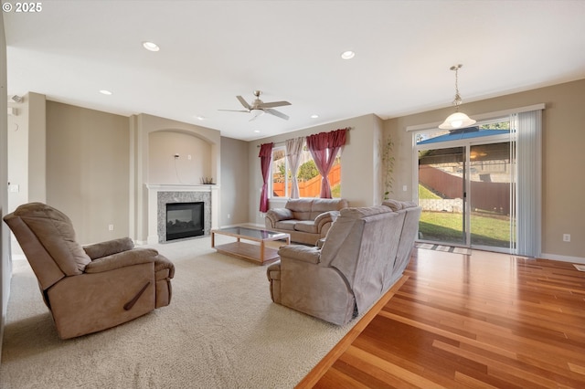 living room with a premium fireplace, ceiling fan, and light hardwood / wood-style floors