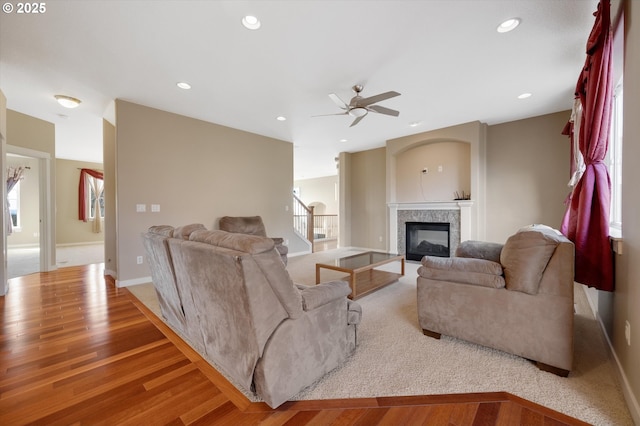 living room featuring ceiling fan, a high end fireplace, and light hardwood / wood-style floors