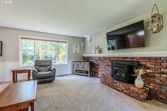 living area featuring a wood stove, a textured ceiling, a wainscoted wall, and carpet flooring