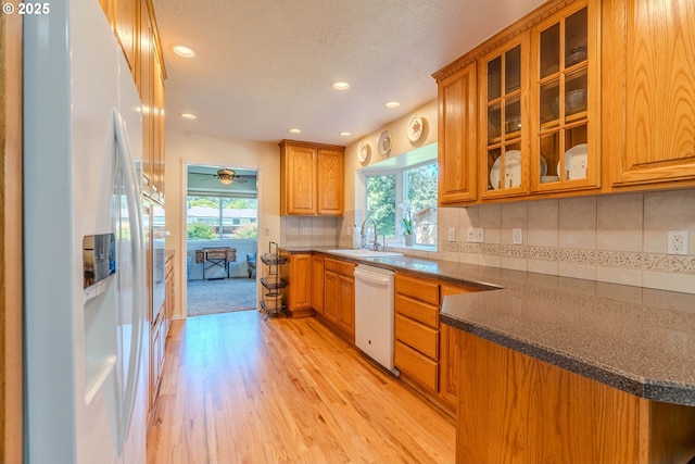 kitchen featuring white appliances, brown cabinets, recessed lighting, and light wood-style flooring