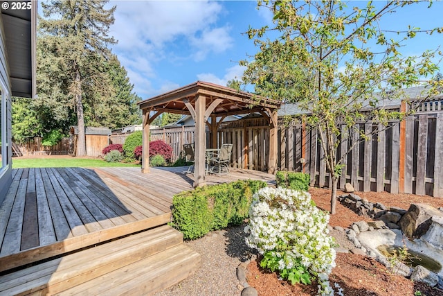 wooden terrace featuring an outdoor structure, a gazebo, a fenced backyard, and a shed