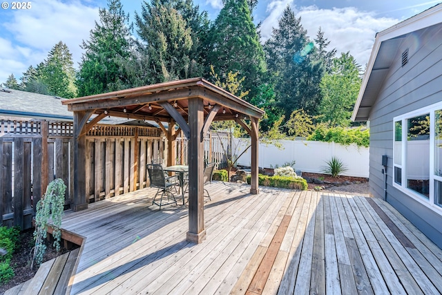 deck featuring a fenced backyard, a gazebo, and outdoor dining area