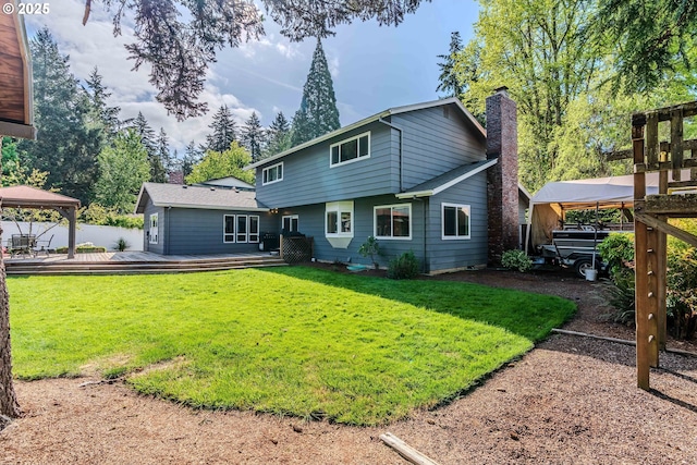 rear view of property with a lawn, a gazebo, a chimney, and a deck