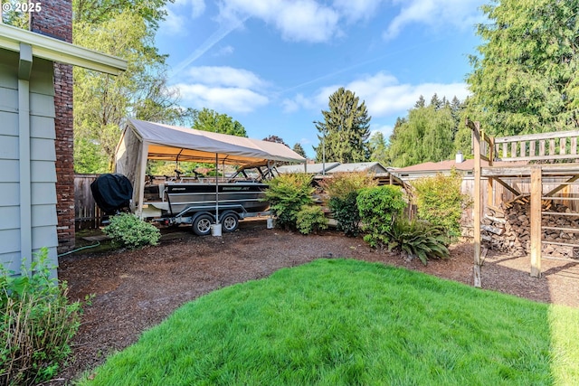 view of yard featuring dirt driveway, fence, and a carport