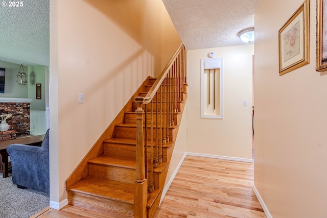 stairs featuring baseboards, a textured ceiling, and wood finished floors