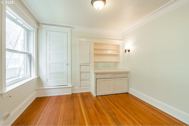 interior space featuring built in features, crown molding, light wood-style flooring, and baseboards