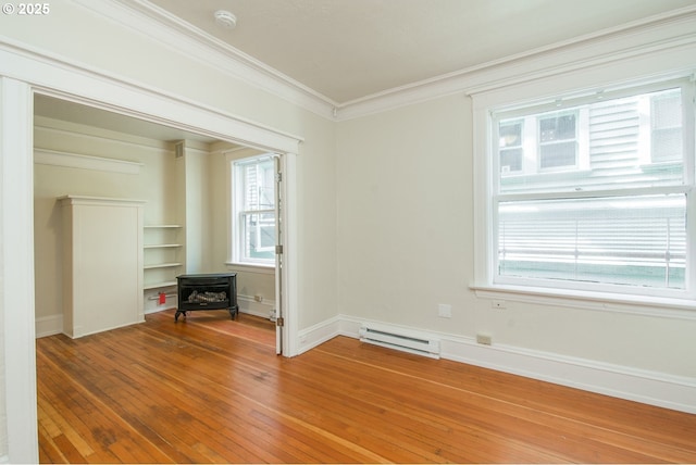 unfurnished room with light wood-style flooring, a baseboard heating unit, baseboards, and ornamental molding