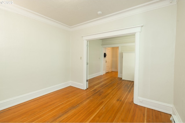 spare room with ornamental molding, light wood-style flooring, and baseboards