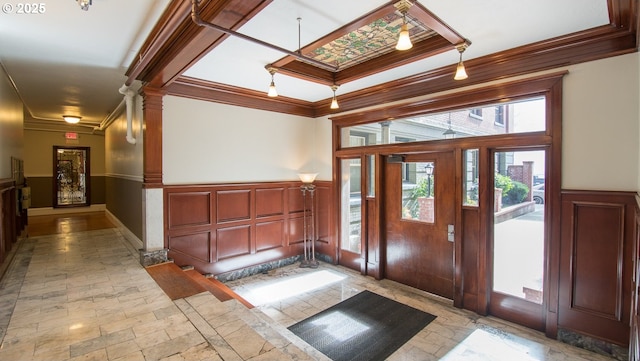 foyer entrance with wainscoting, crown molding, and stone tile floors