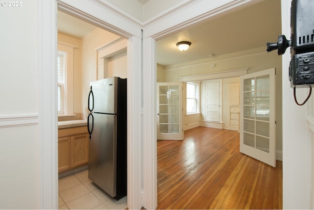 kitchen featuring light wood-type flooring, freestanding refrigerator, french doors, and tile countertops