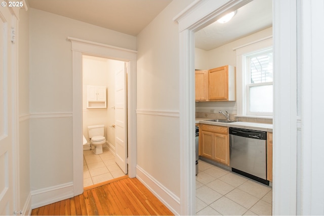 hall with light wood-style floors, baseboards, and a sink