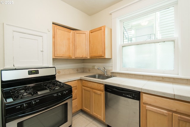 kitchen featuring tile countertops, light brown cabinets, stainless steel appliances, and a sink