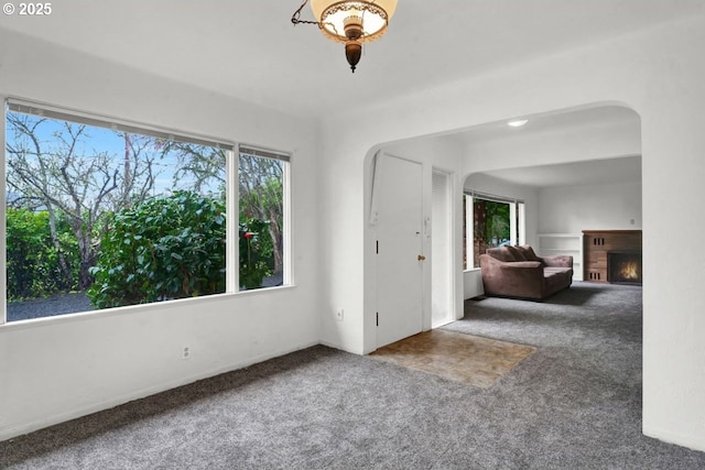 1541 Buckhorn Rd, Roseburg, OR 97470 - unfurnished living room featuring arched walkways, carpet, and a lit fireplace