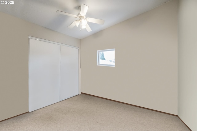 unfurnished bedroom with a closet, light colored carpet, ceiling fan, and baseboards