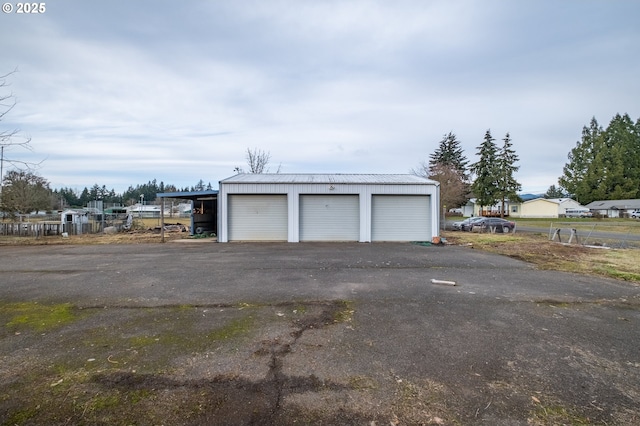 garage featuring a detached garage and fence