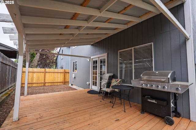 wooden terrace with a grill and a fenced backyard