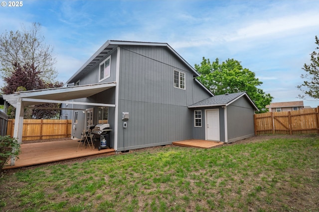 back of house featuring a lawn, a deck, and a fenced backyard