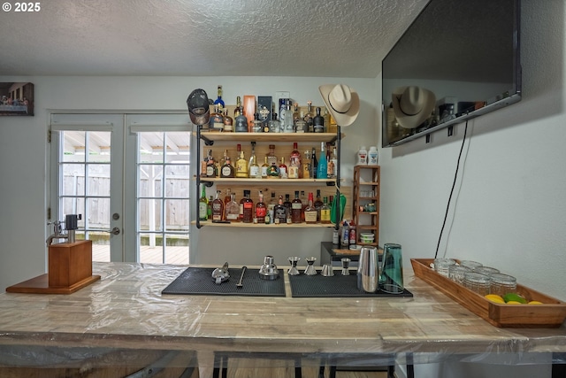 bar featuring a textured ceiling, french doors, and bar