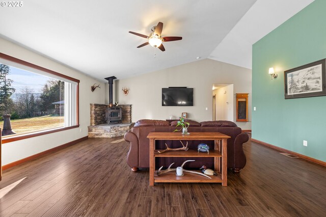 living room featuring vaulted ceiling, ceiling fan, a wood stove, and dark hardwood / wood-style floors