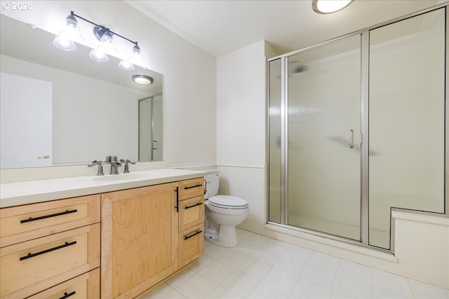 bathroom with wainscoting, toilet, a shower stall, and vanity