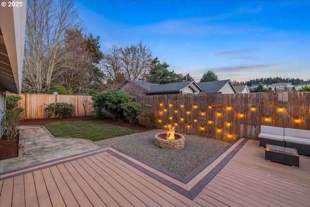 deck at dusk featuring a yard, a fenced backyard, and an outdoor living space with a fire pit