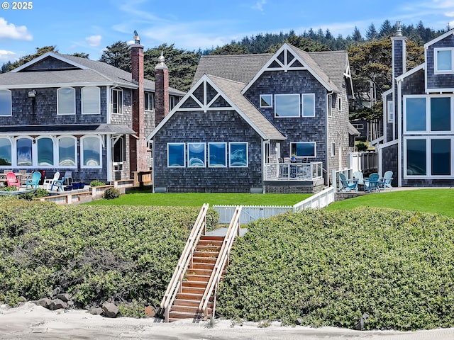 3764 Pacific Ave, Cannon Beach, OR 97110 - view of front of property featuring stairway, a front lawn, a shingled roof, and a chimney