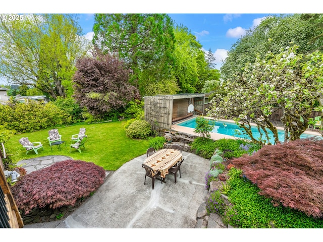 pool featuring a lawn, a patio, and an outbuilding