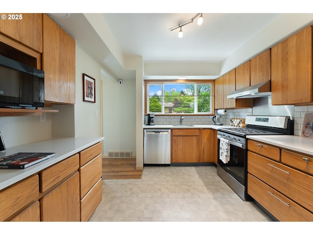 kitchen featuring visible vents, light countertops, under cabinet range hood, a sink, and stainless steel appliances