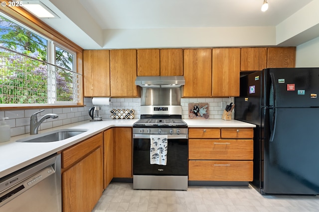 kitchen featuring a sink, light countertops, brown cabinetry, stainless steel appliances, and under cabinet range hood