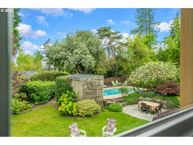 view of pool featuring a fenced backyard, a fenced in pool, an outbuilding, a patio area, and a lawn