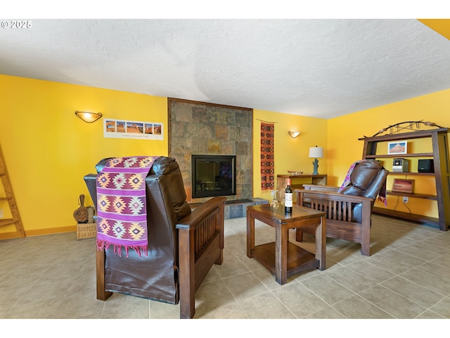 tiled living area with baseboards, a textured ceiling, and a large fireplace