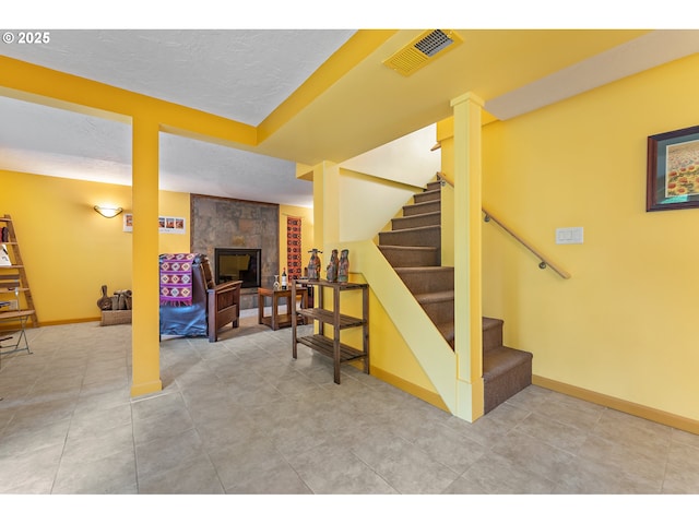 interior space with visible vents, stairs, a fireplace, baseboards, and a textured ceiling