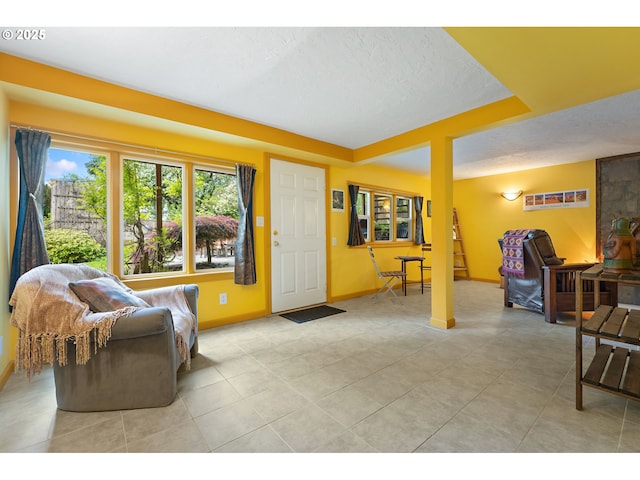 living area featuring baseboards, light tile patterned flooring, and a textured ceiling