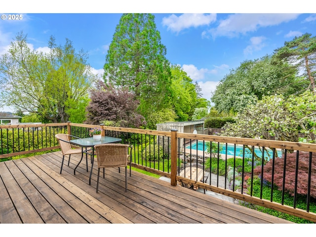 deck with a storage unit, outdoor dining space, a fenced in pool, a fenced backyard, and an outbuilding