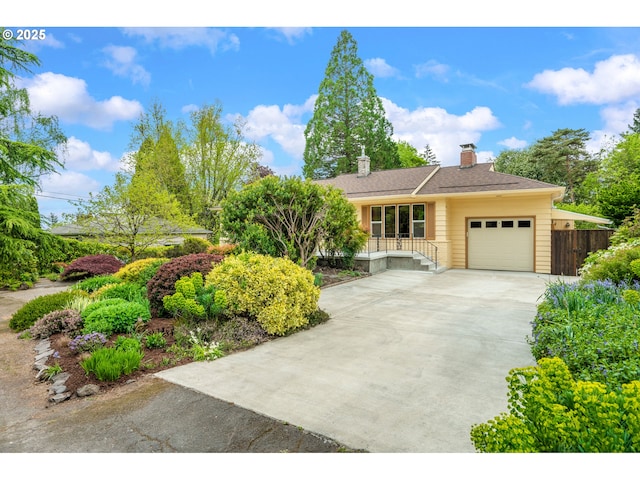view of front of property with concrete driveway, fence, a chimney, and a garage