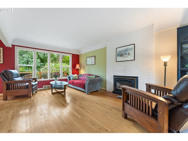 living room with a fireplace, light wood-type flooring, and visible vents