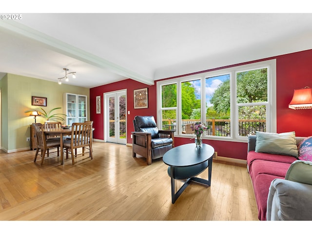 living room featuring light wood-style floors, baseboards, and beamed ceiling