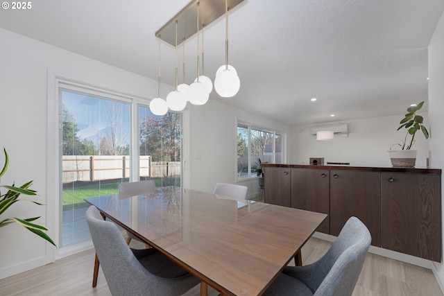 dining area with light hardwood / wood-style floors and a wall mounted air conditioner