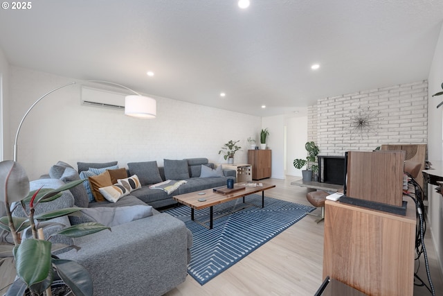 living room with brick wall, a wall unit AC, and light hardwood / wood-style flooring