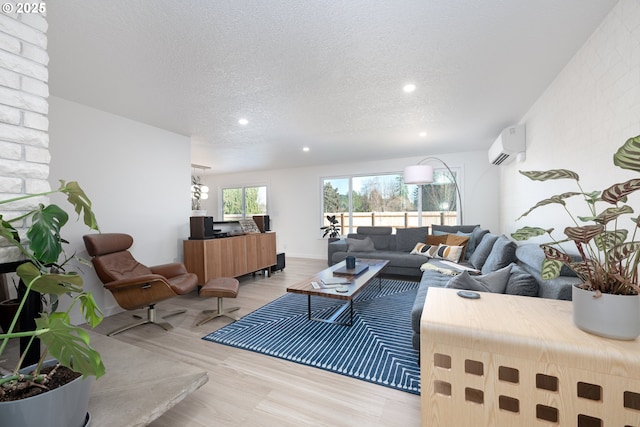 living room featuring light hardwood / wood-style flooring, a textured ceiling, and a wall mounted AC