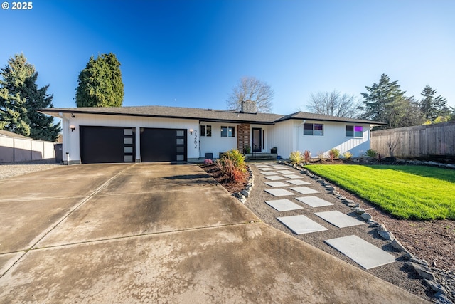 ranch-style house featuring a garage, a front yard, concrete driveway, and fence