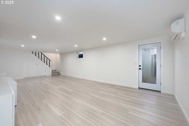 unfurnished living room featuring a wall mounted air conditioner, light hardwood / wood-style floors, and washer / dryer