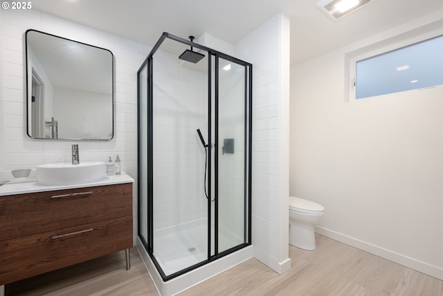 bathroom with vanity, hardwood / wood-style flooring, toilet, and a shower with door