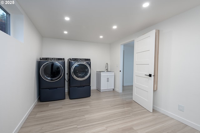 laundry room featuring light wood-type flooring, washing machine and dryer, cabinets, and sink