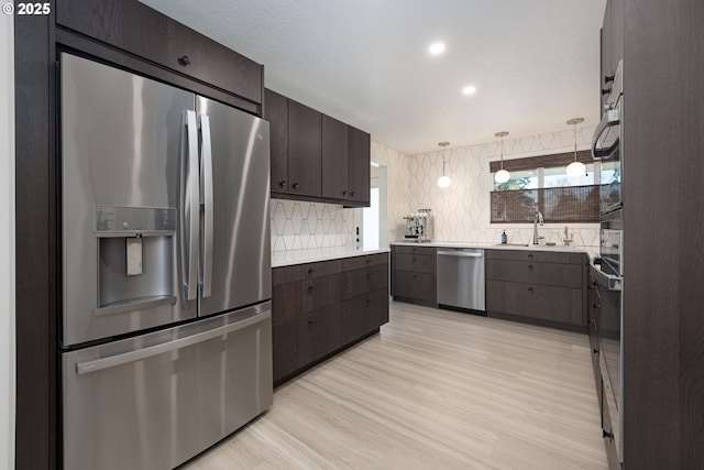 kitchen with tasteful backsplash, dark brown cabinetry, stainless steel appliances, sink, and decorative light fixtures